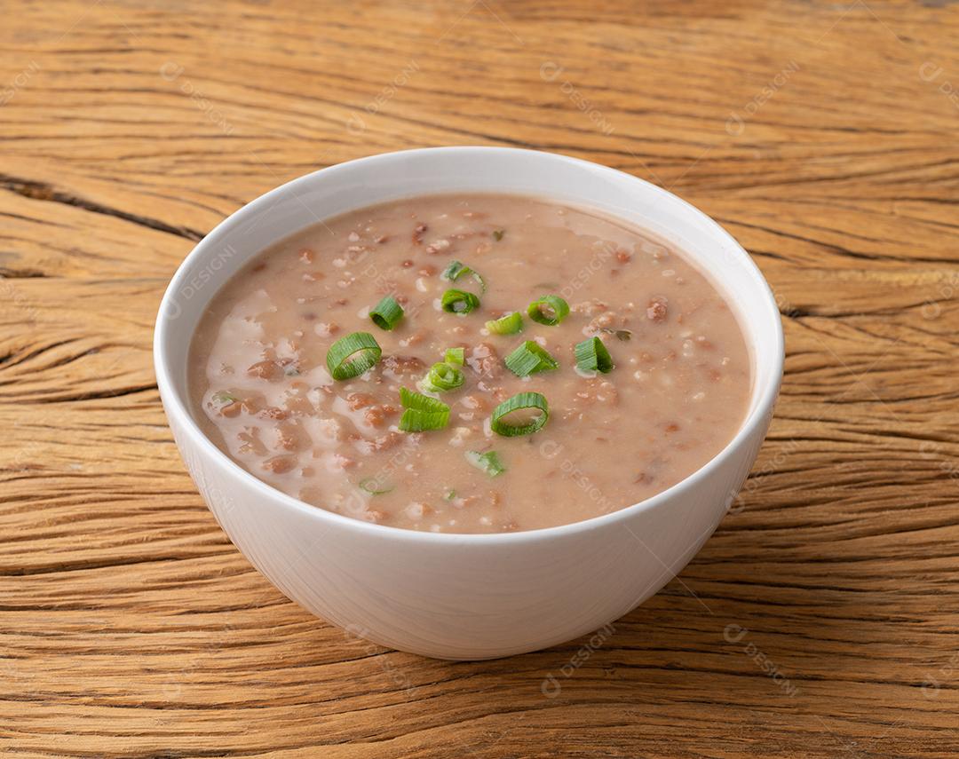 Sopa de feijão marrom em uma tigela sobre a mesa de madeira.