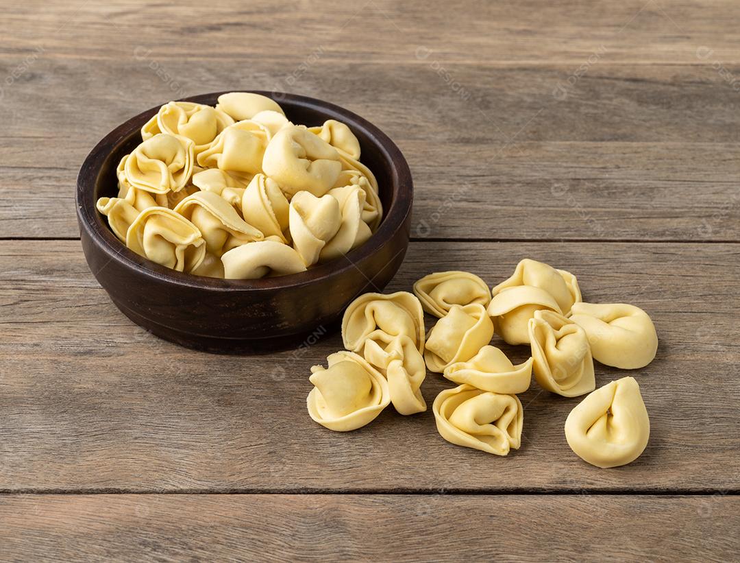 Cappelletti cru ou tortellini em uma tigela sobre a mesa de madeira.