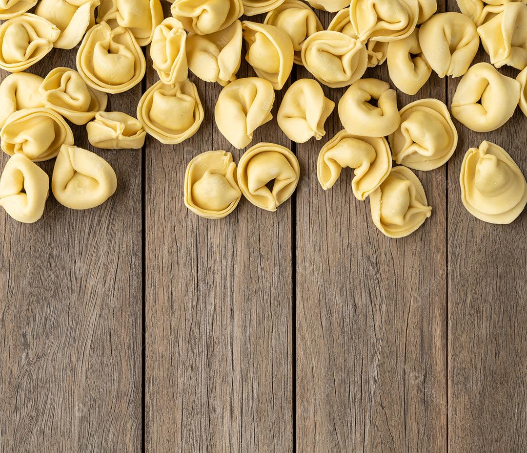 Cappelletti cru ou tortellini sobre mesa de madeira com espaço de cópia.