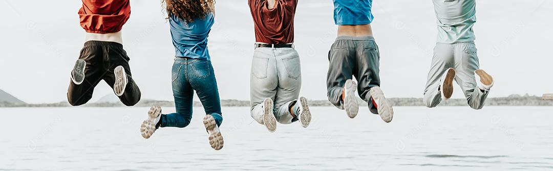 grupo de alegres jovens amigos multirraciais saltam sobre fundo branco