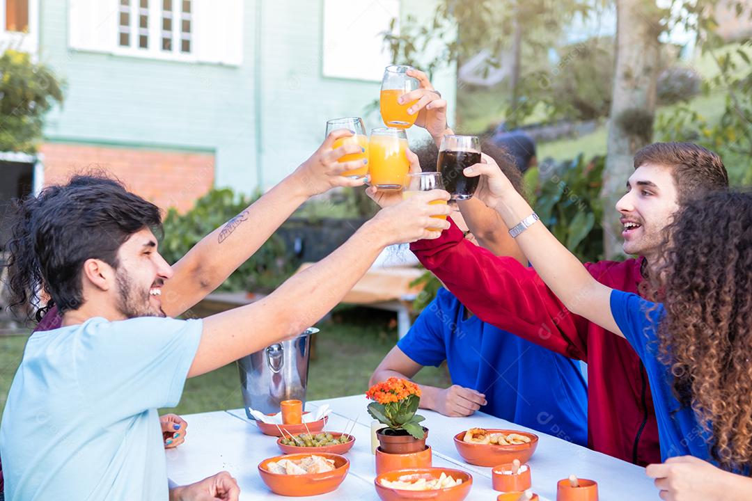 Grupo de amigos do milênio se divertindo do lado de fora brindando bebidas na festa no jardim - Conceito de estilo de vida