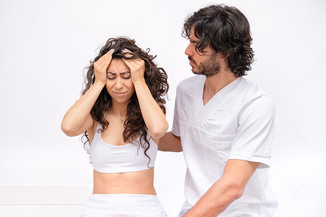 mulher na clínica em consulta com um jovem médico fisioterapeuta e reclamando de dores de cabeça
