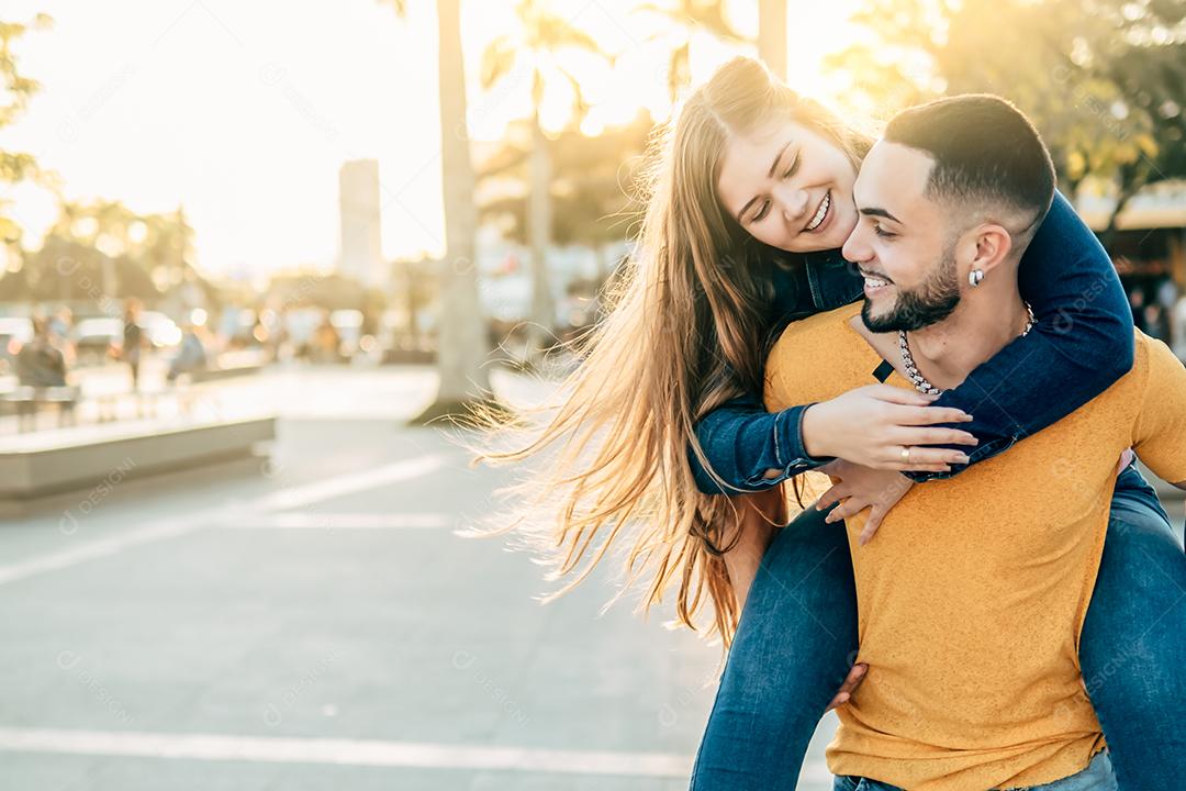 garota nas costas do namorado se divertindo nas ruas da cidade - amigos felizes rindo juntos nas férias