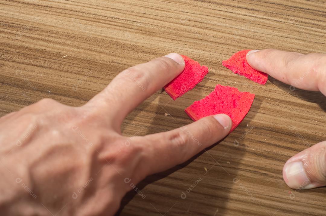 Trabalho de coração partido em pedaços, biscoito em forma de coração partido em uma mesa de madeira.