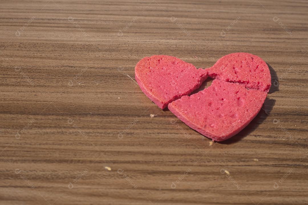 Trabalho de coração partido em pedaços, biscoito em forma de coração partido em uma mesa de madeira.