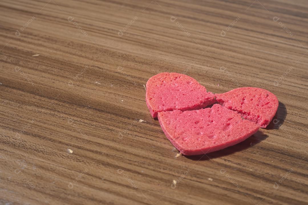 Trabalho de coração partido em pedaços, biscoito em forma de coração partido em uma mesa de madeira.