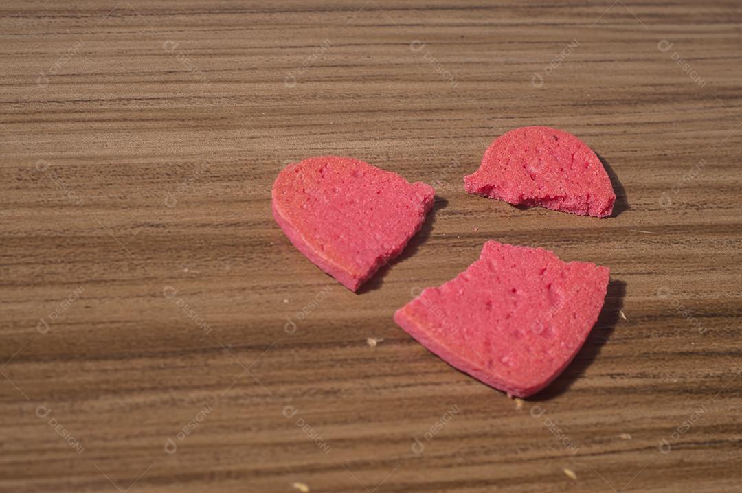 Trabalho de coração partido em pedaços, biscoito em forma de coração partido em uma mesa de madeira.