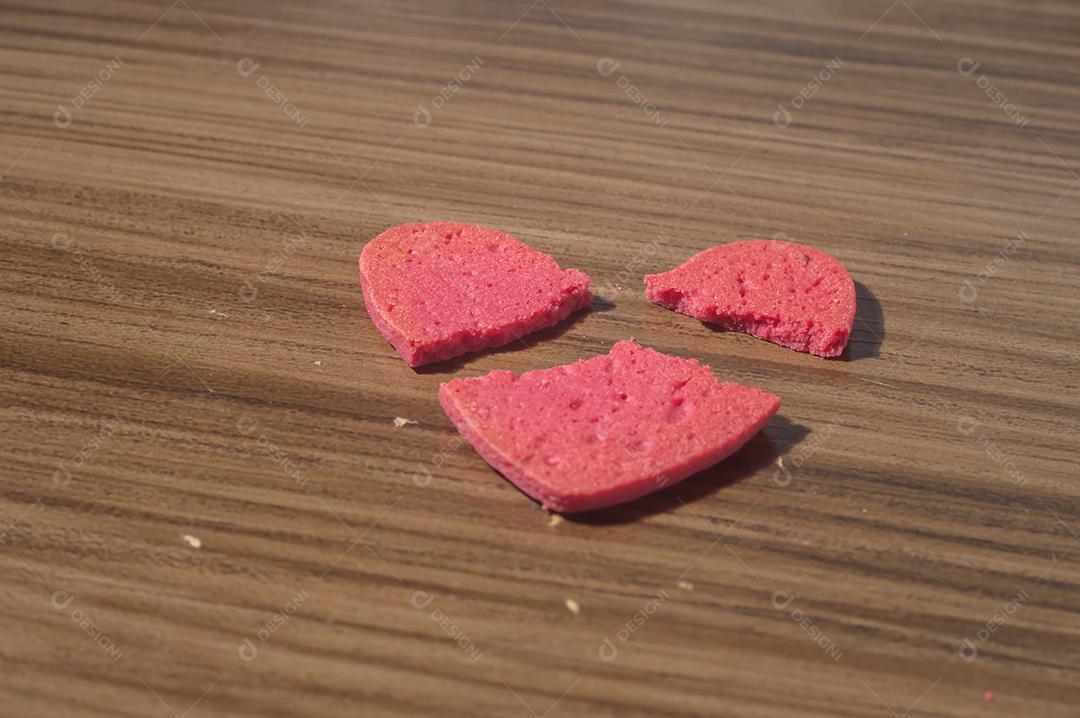 Trabalho de coração partido em pedaços, biscoito em forma de coração partido em uma mesa de madeira.