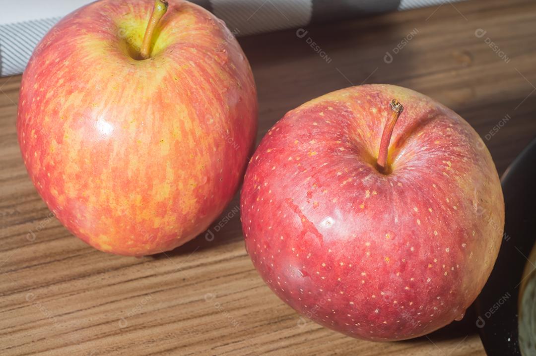 Pães e maçãs em um tablet de madeira e luz suave.
