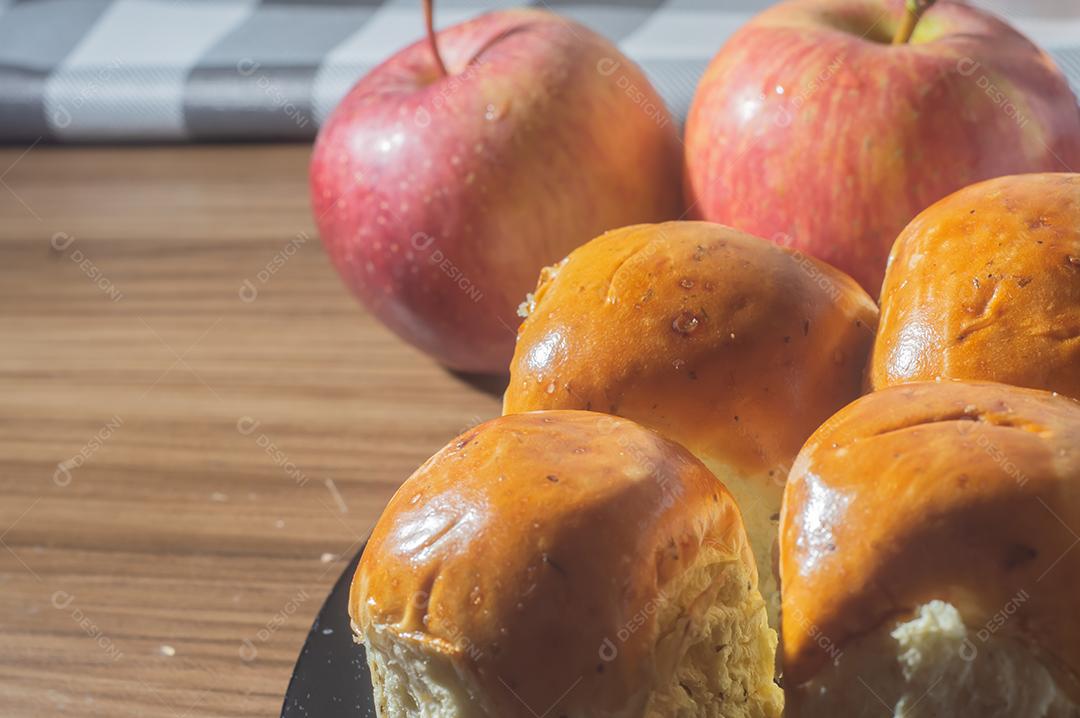 Pães e maçãs em um tablet de madeira e luz suave.