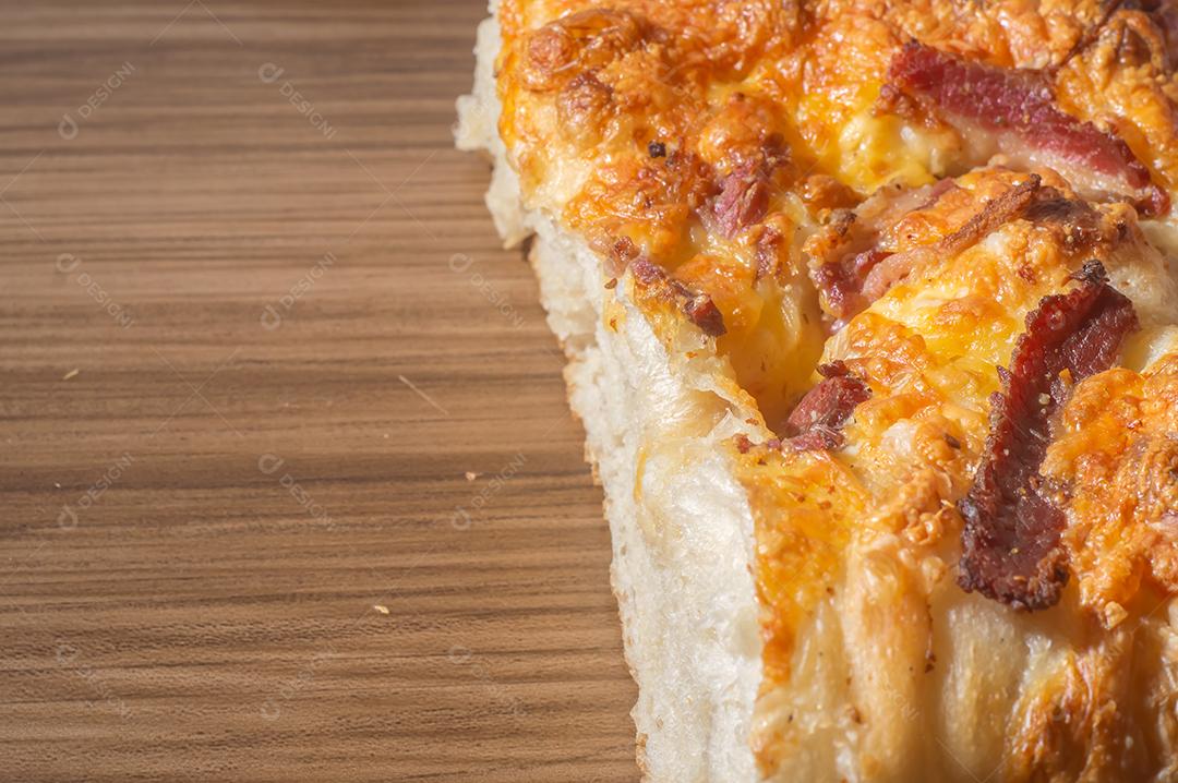 Foccacia italiana recém-assada com queijo amarelo e pastrami, em um tablet de madeira