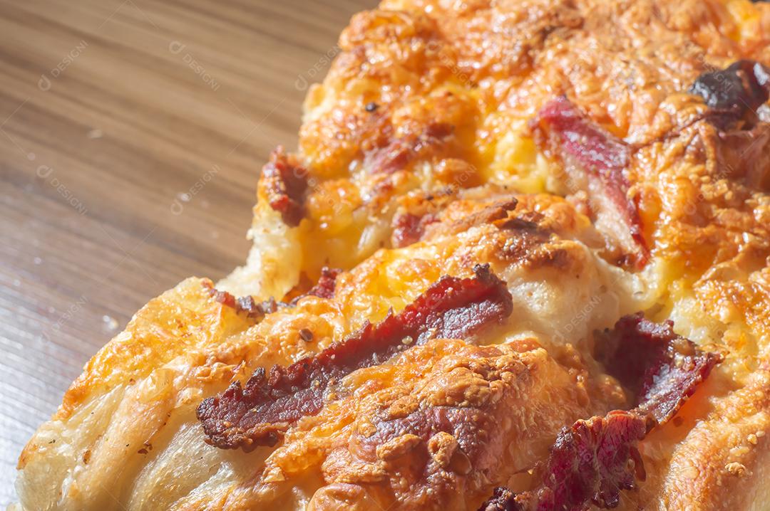 Foccacia italiana recém-assada com queijo amarelo e pastrami, em um tablet de madeira