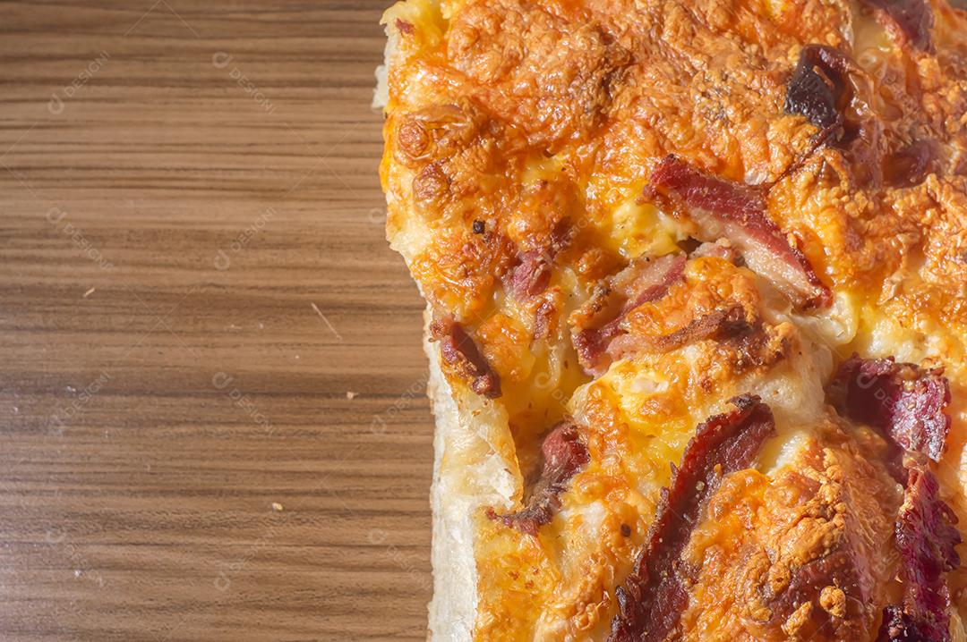 Foccacia italiana recém-assada com queijo amarelo e pastrami, em um tablet de madeira