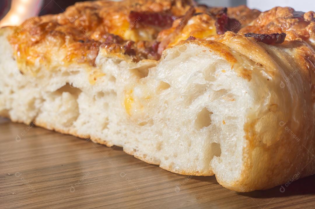 Foccacia italiana recém-assada com queijo amarelo e pastrami, em um tablet de madeira