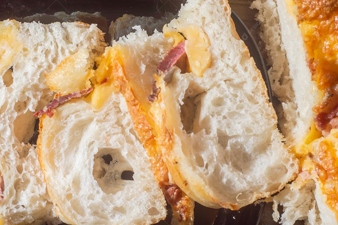 Foccacia italiana recém-assada com queijo amarelo e pastrami, em um tablet de madeira