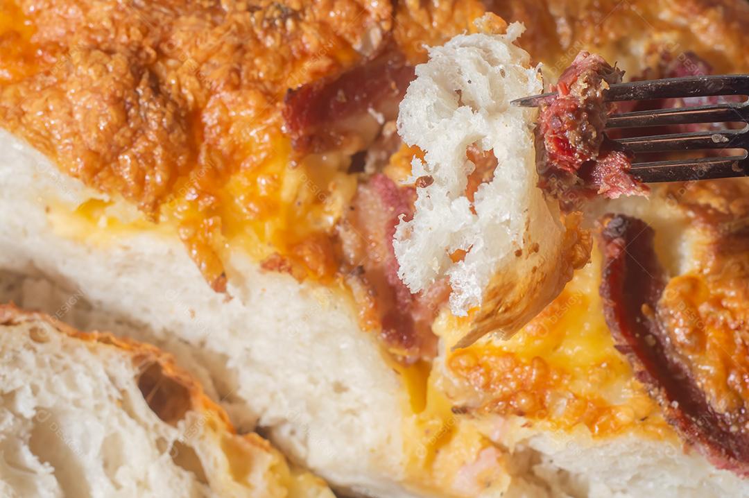 Foccacia italiana recém-assada com queijo amarelo e pastrami, em um tablet de madeira