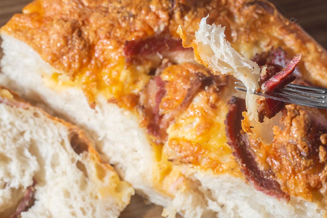 Foccacia italiana recém-assada com queijo amarelo e pastrami, em um tablet de madeira