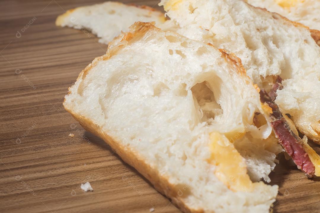 Foccacia italiana recém-assada com queijo amarelo e pastrami, em um tablet de madeira