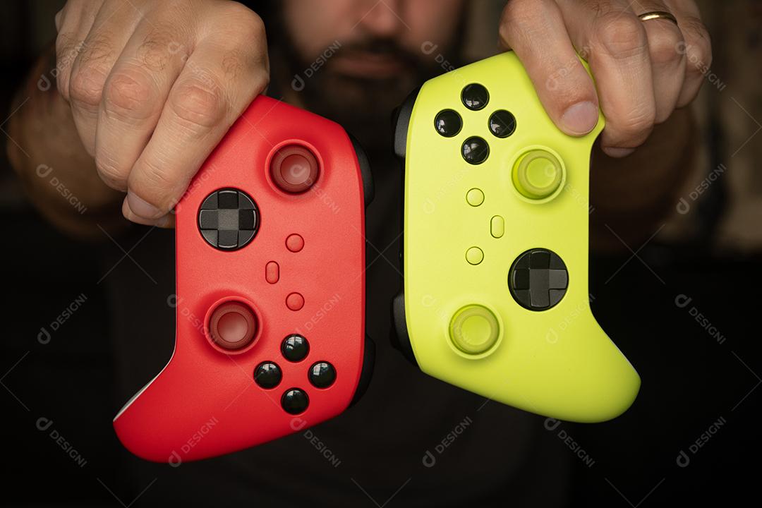 Homem segura controladores de jogos vermelhos e verdes