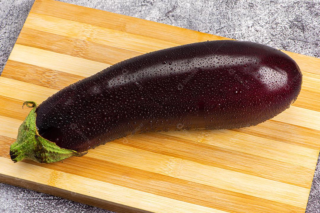 Berinjela sob tábua de madeira sendo aspergida com água para ser preparada para salada.