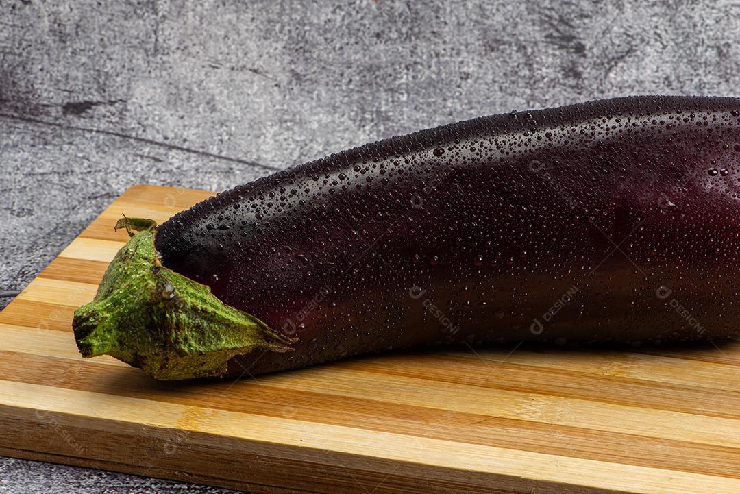 Berinjela sob tábua de madeira sendo aspergida com água para ser preparada para salada.