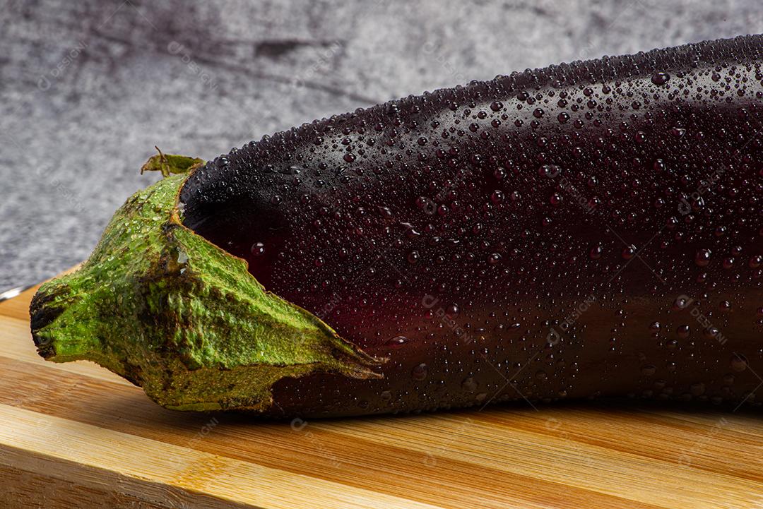 Berinjela sob tábua de madeira sendo aspergida com água para ser preparada para salada.