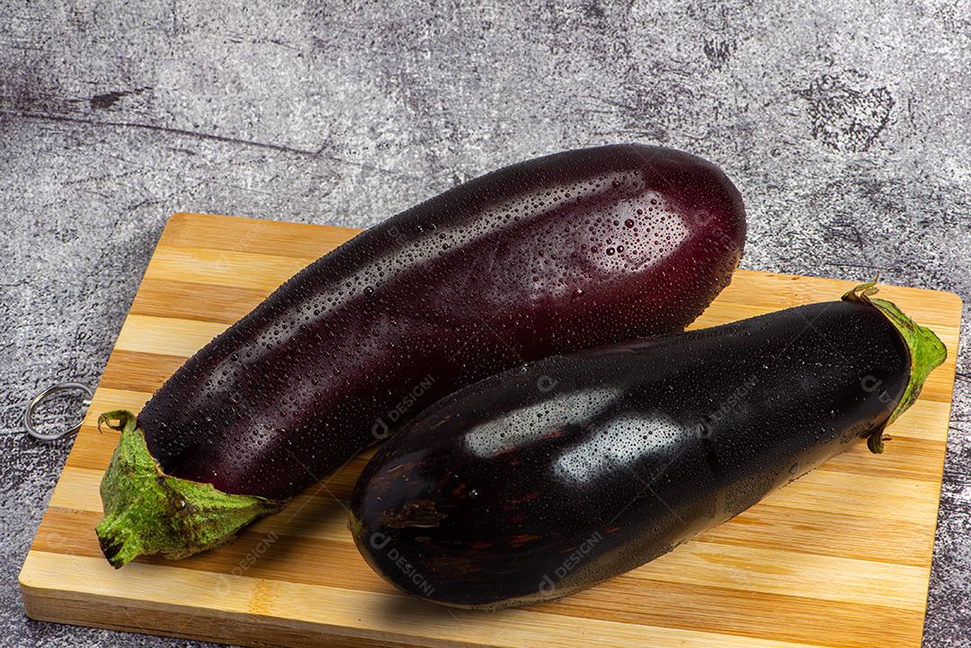 Berinjela sob tábua de madeira sendo aspergida com água para ser preparada para salada.