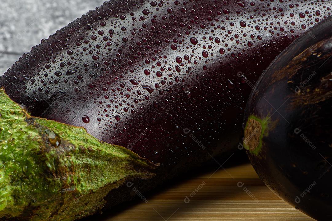 Berinjela sob tábua de madeira sendo aspergida com água para ser preparada para salada.