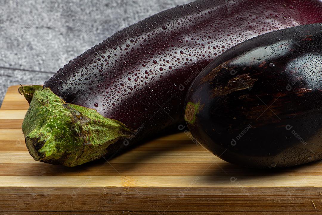 Berinjela sob tábua de madeira sendo aspergida com água para ser preparada para salada.