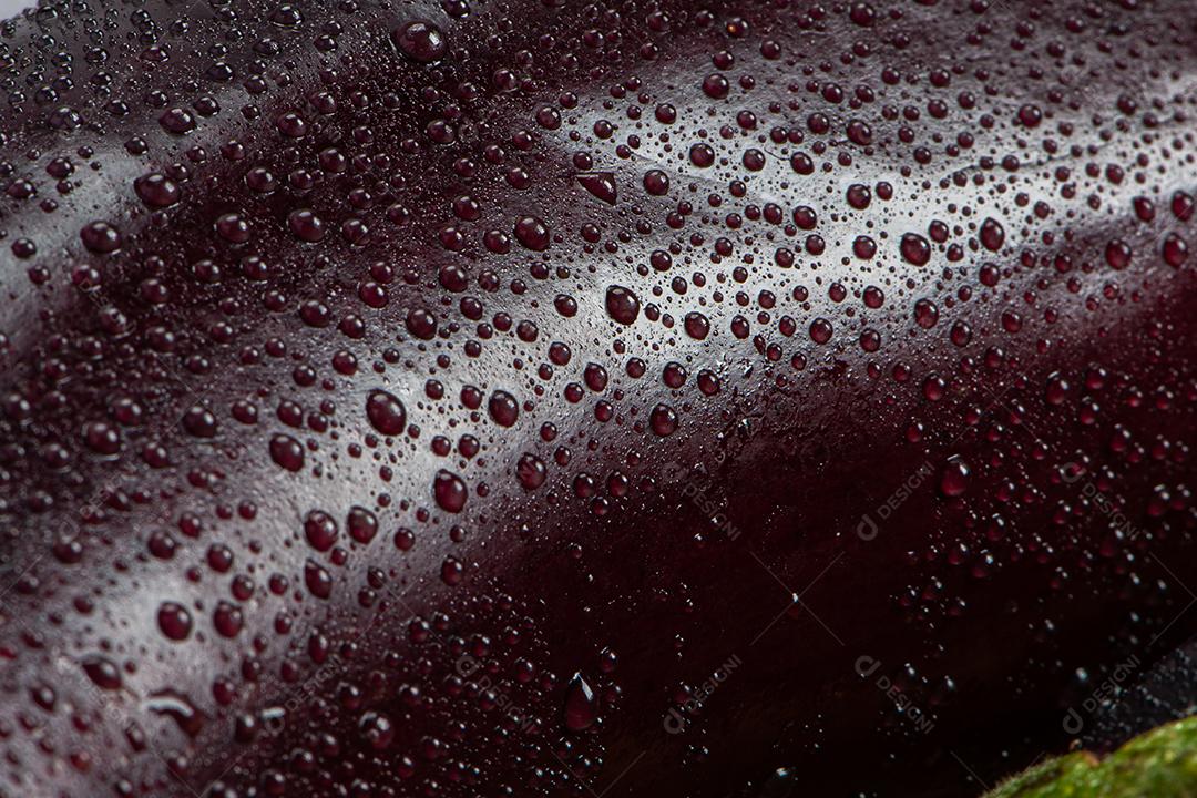 Berinjela sob tábua de madeira sendo aspergida com água para ser preparada para salada.