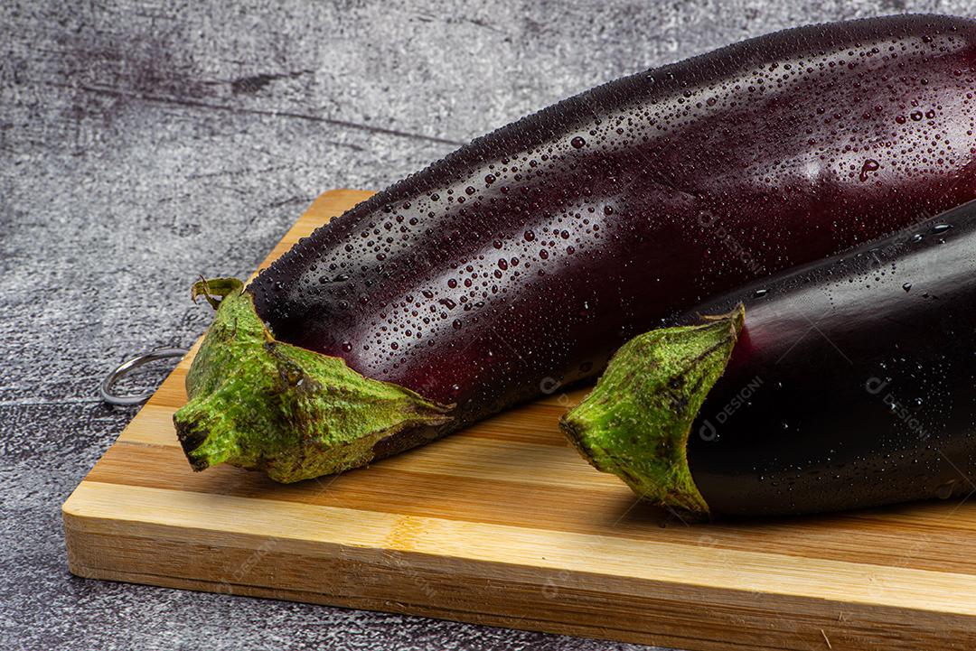 Berinjela sob tábua de madeira sendo aspergida com água para ser preparada para salada.
