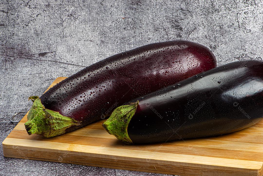 Berinjela sob tábua de madeira sendo aspergida com água para ser preparada para salada.