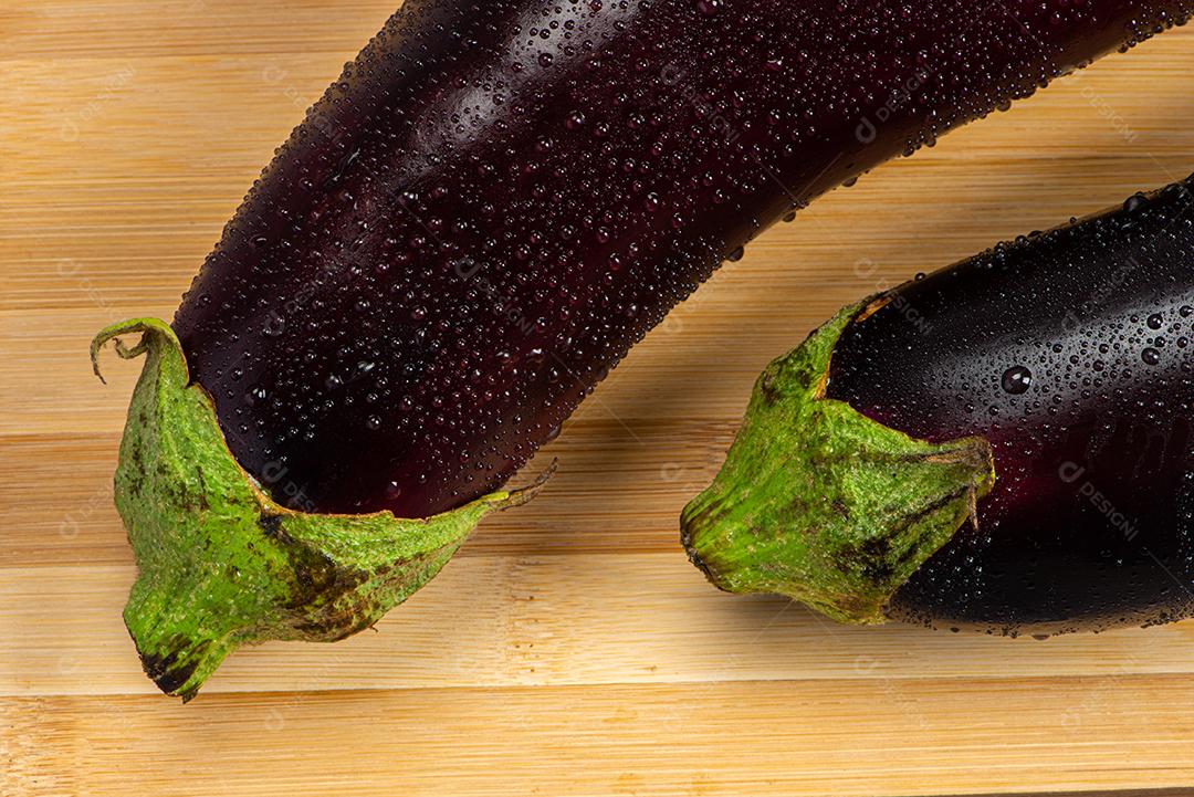 Berinjela sob tábua de madeira sendo aspergida com água para ser preparada para salada.