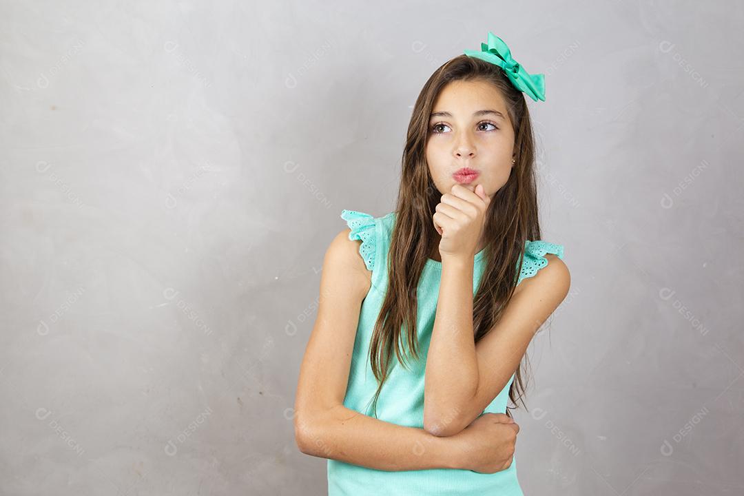 Linda menina de dez anos pensativa em fundo cinza