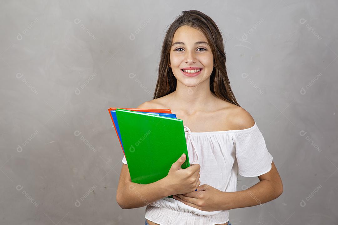 Jovem garota caucasiana com notebooks nas mãos, apontando  Dia do estudante. De volta à escola.