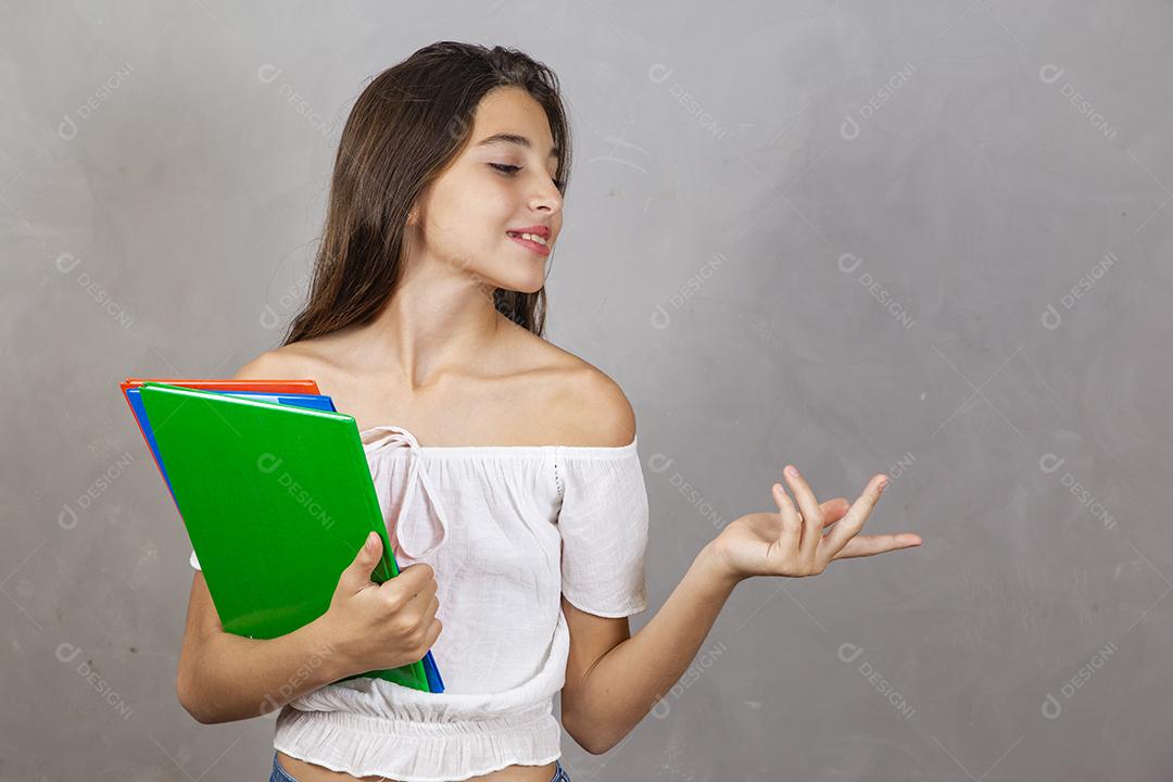 Young caucasian girl with notebooks in hands pointing to text. Student's day. Back to school.