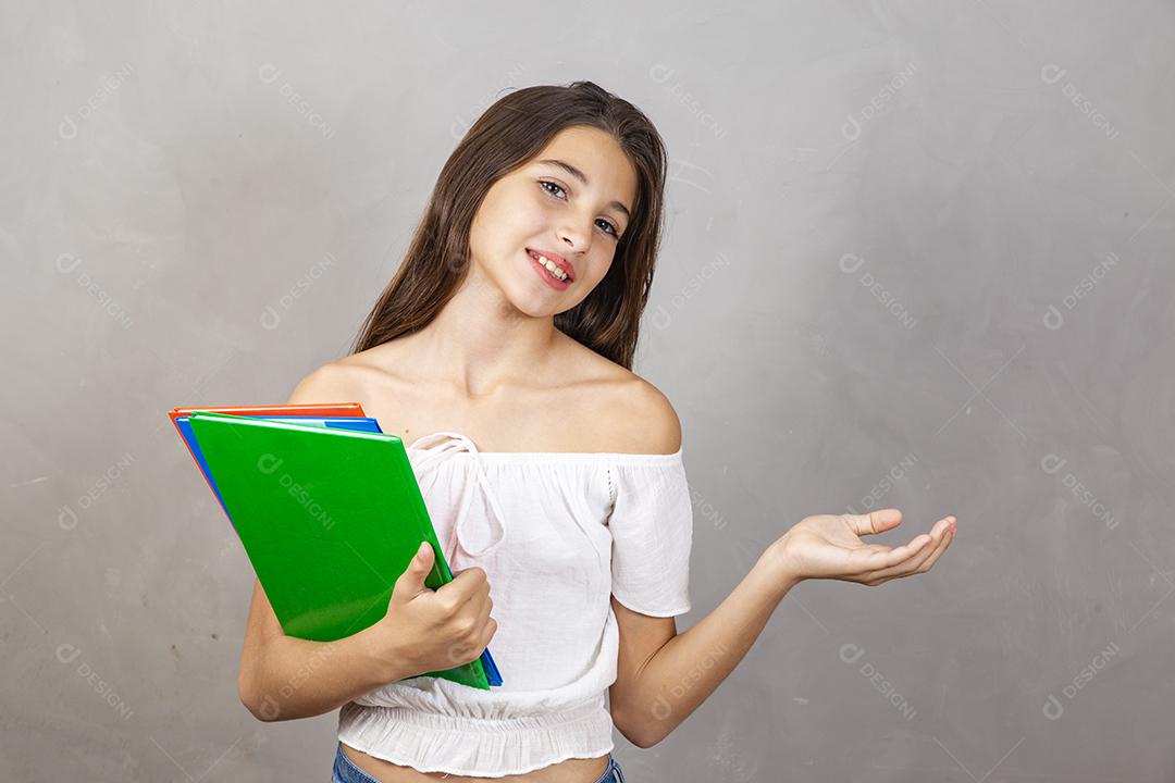 Jovem garota caucasiana com notebooks nas mãos, apontando para texto. Dia do estudante. De volta à escola.