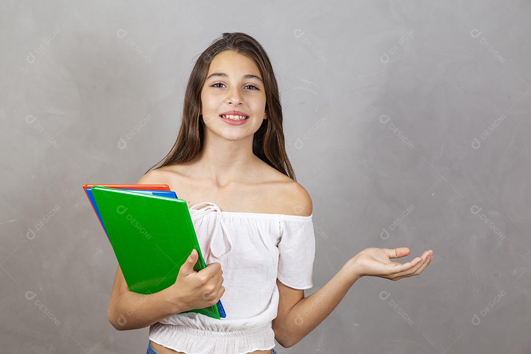 Jovem garota caucasiana com notebooks nas mãos, apontando para texto. Dia do estudante. De volta à escola.