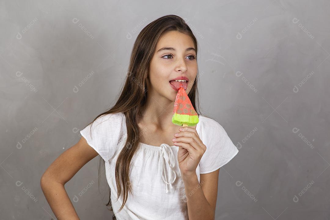 Adorable little girl with delicious ice cream popsicle on gray background