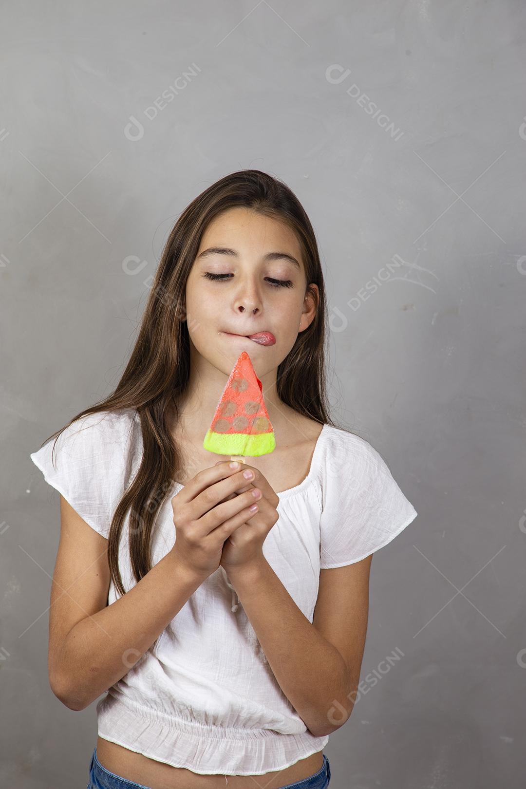 Adorável menina com delicioso picolé de sorvete no fundo cinza