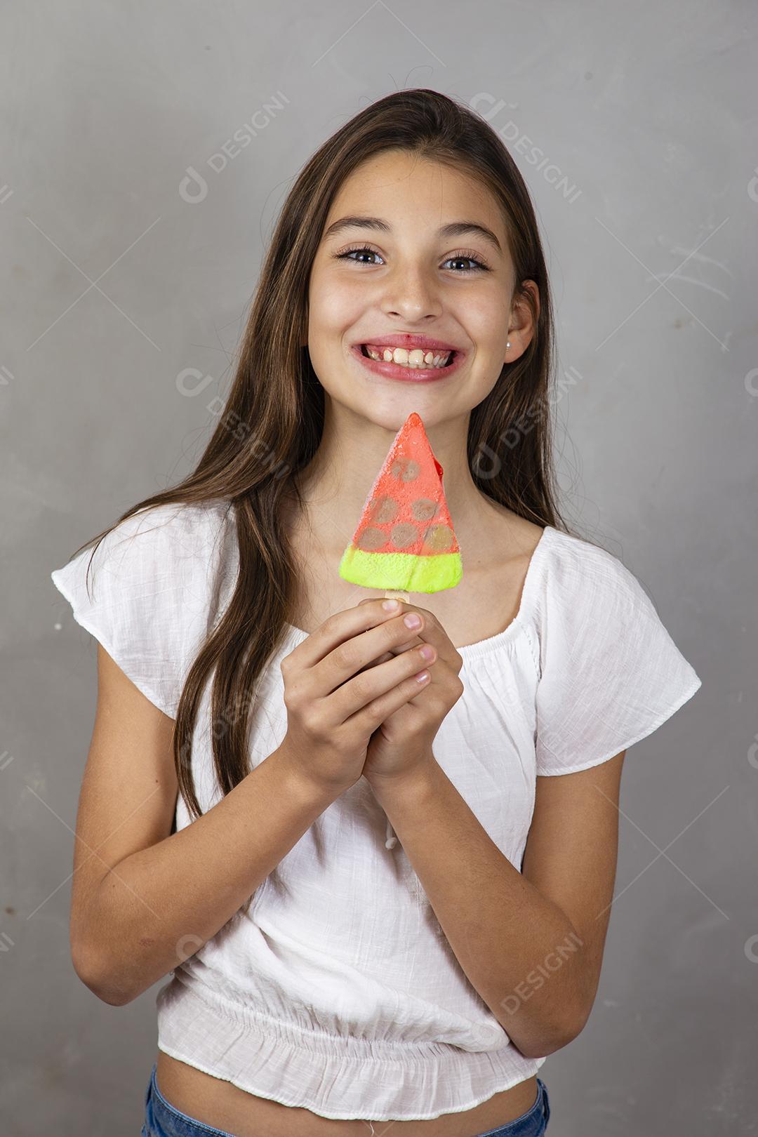 Adorável menina com delicioso picolé de sorvete no fundo cinza