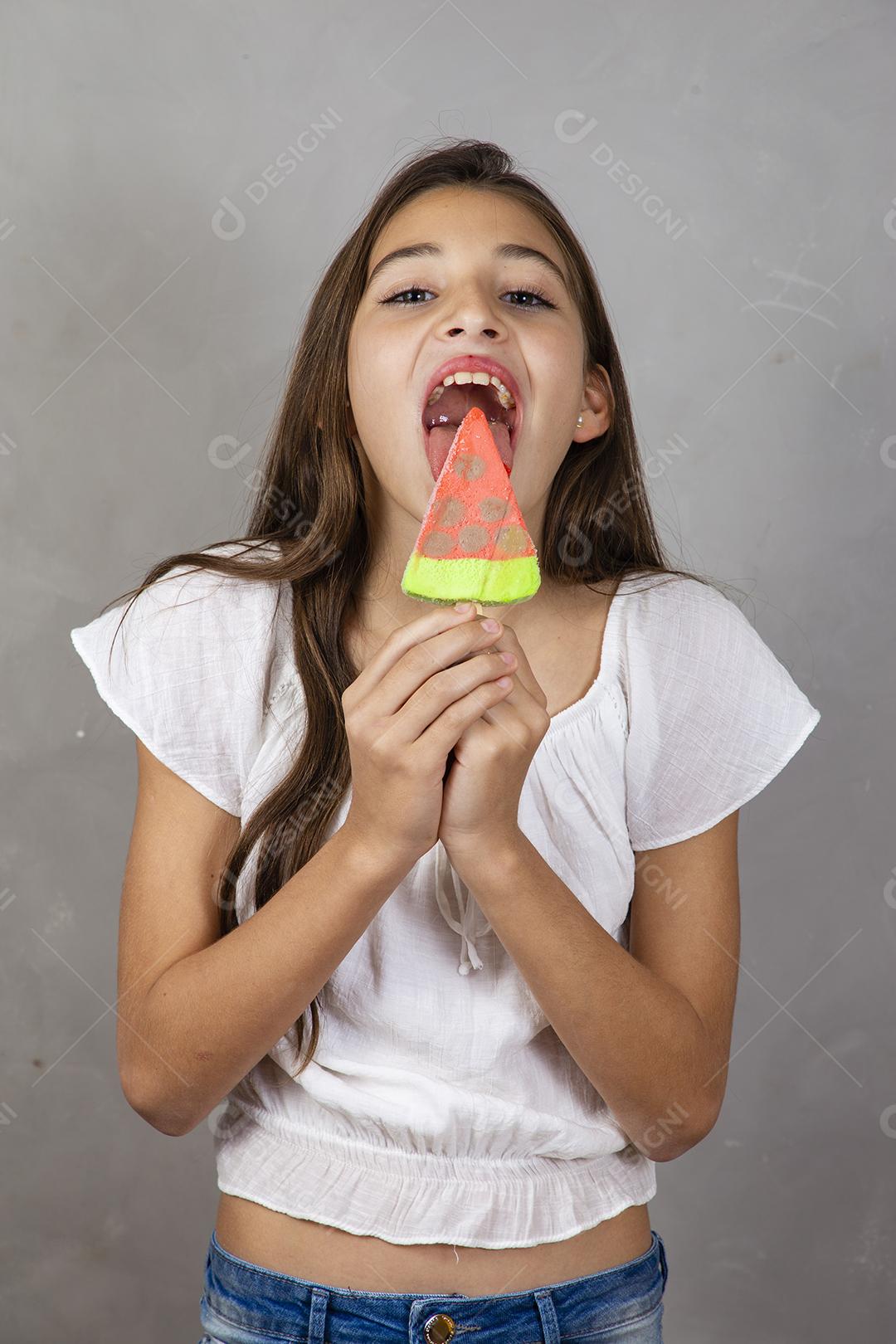 Adorável menina com delicioso picolé de sorvete no fundo cinza