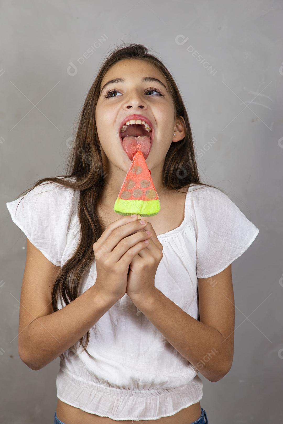 Adorável menina com delicioso picolé de sorvete no fundo cinza