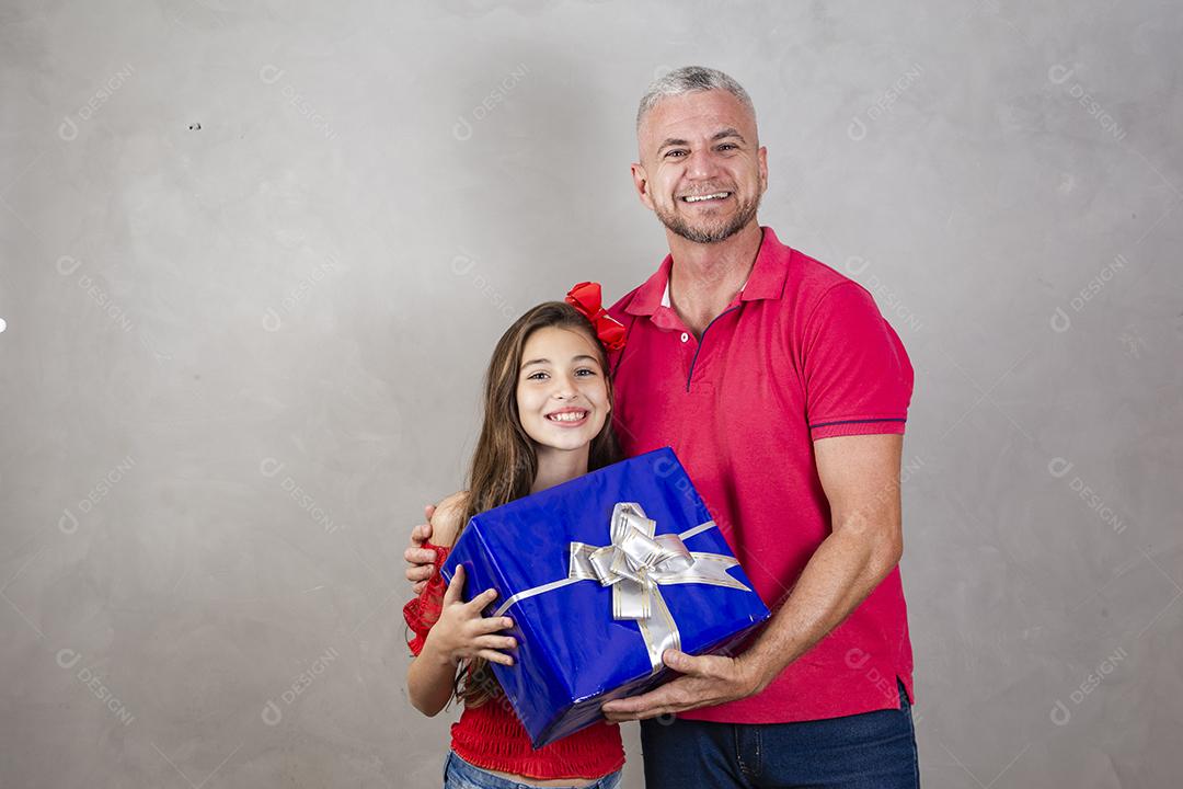 Pai e filha segurando um grande presente em fundo cinza Dia dos Pais, Dia das Crianças ou Dia das Crianças.