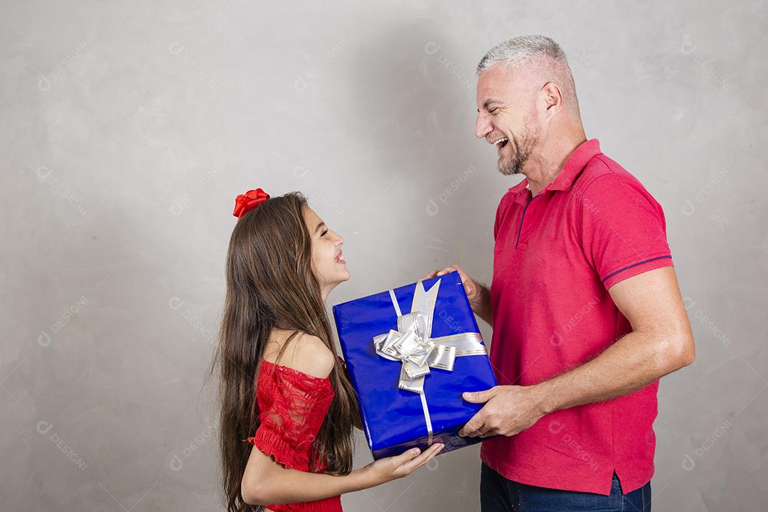 Pai e filha segurando um grande presente em fundo cinza Dia dos Pais, Dia das Crianças ou Dia das Crianças.