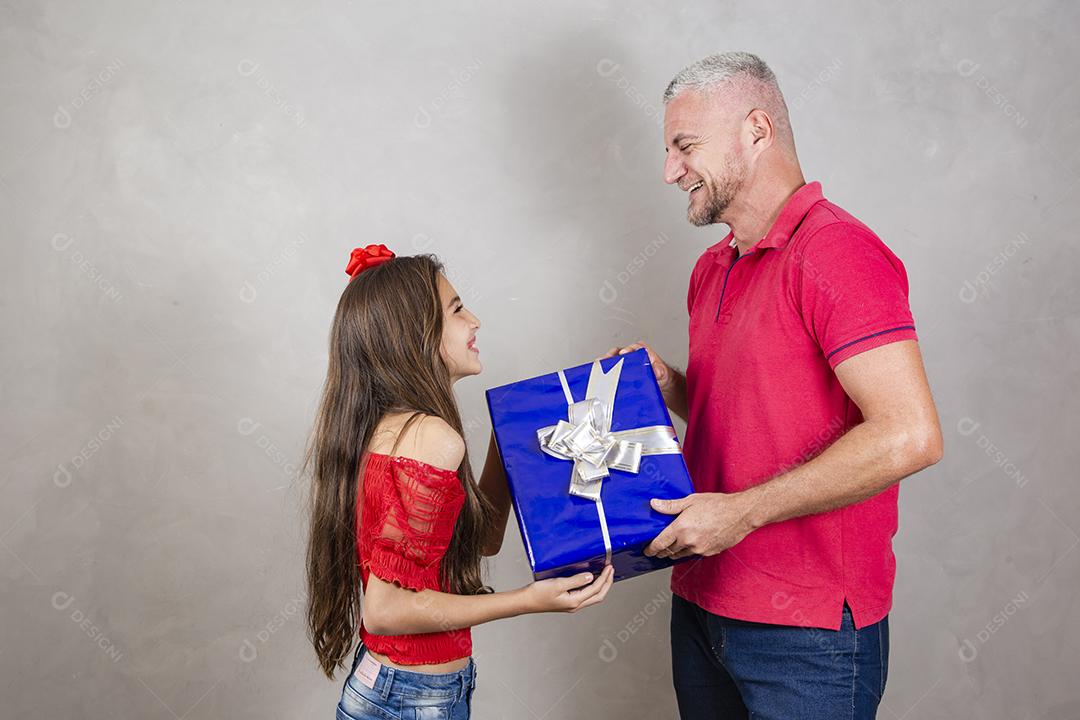 Pai e filha segurando um grande presente em fundo cinza Dia dos Pais, Dia das Crianças ou Dia das Crianças.