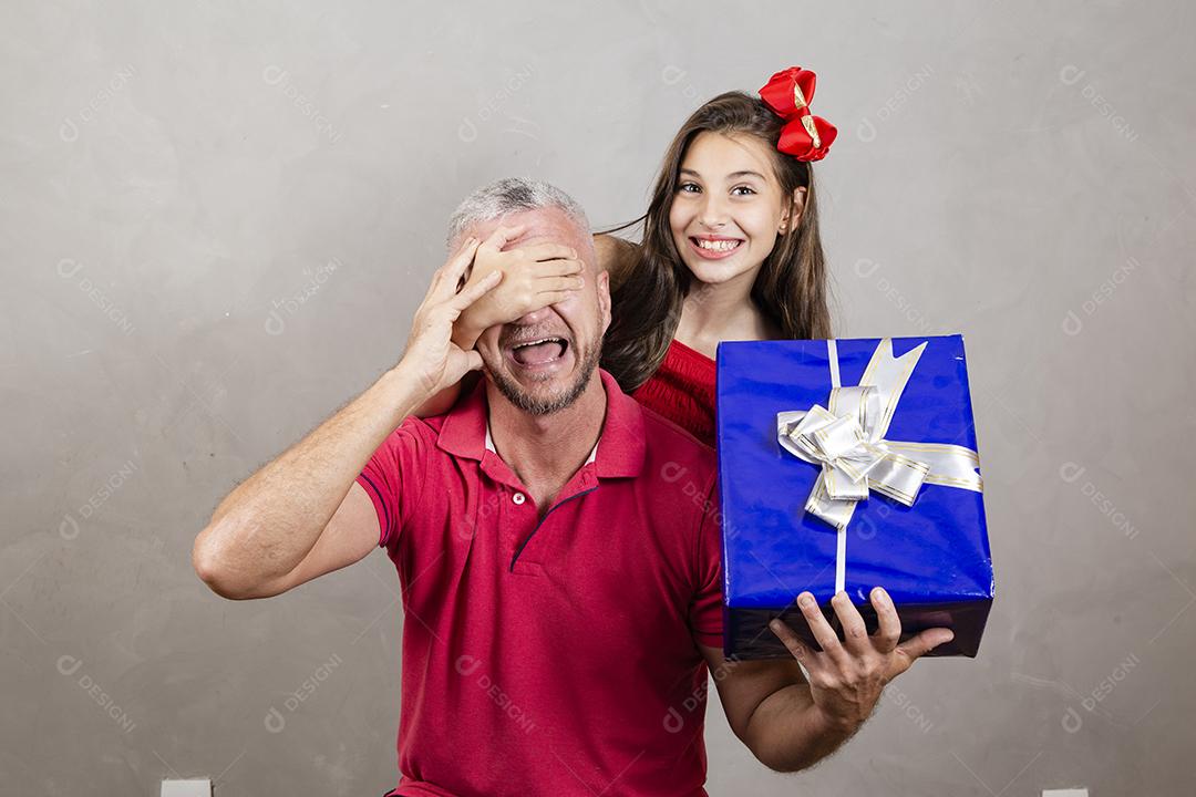 Dia dos Pais! Filha caucasiana cobrindo os olhos do pai segurando um presente de dia dos pais. Surpresa no dia dos pais