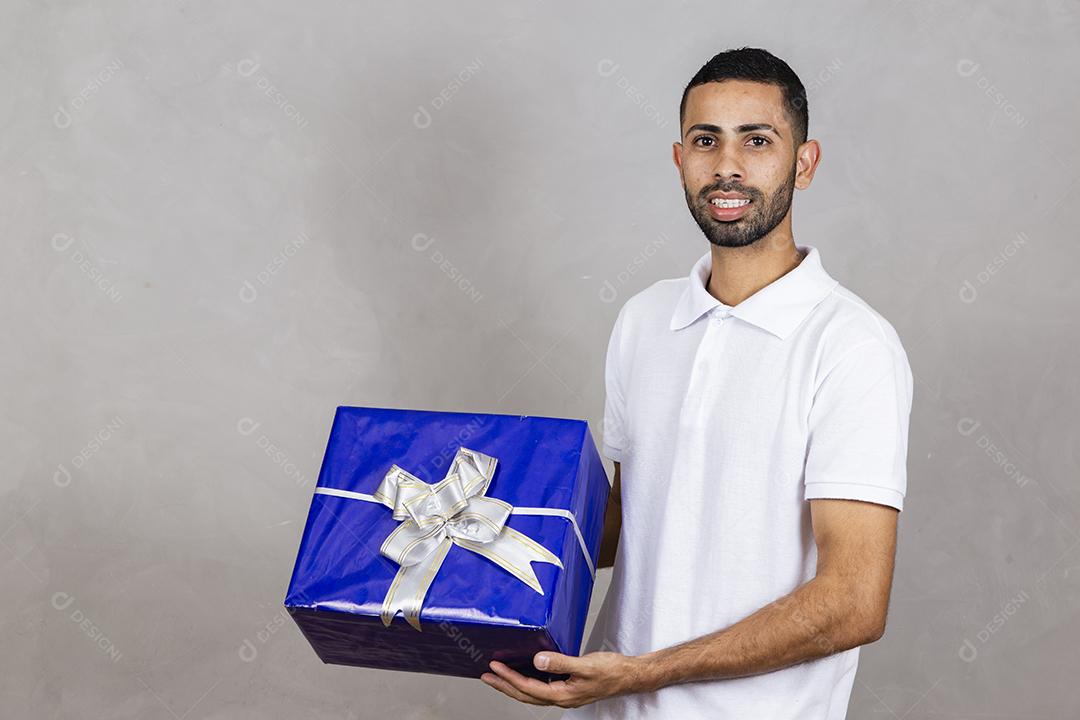 menino segurando uma caixa de presente em fundo cinza