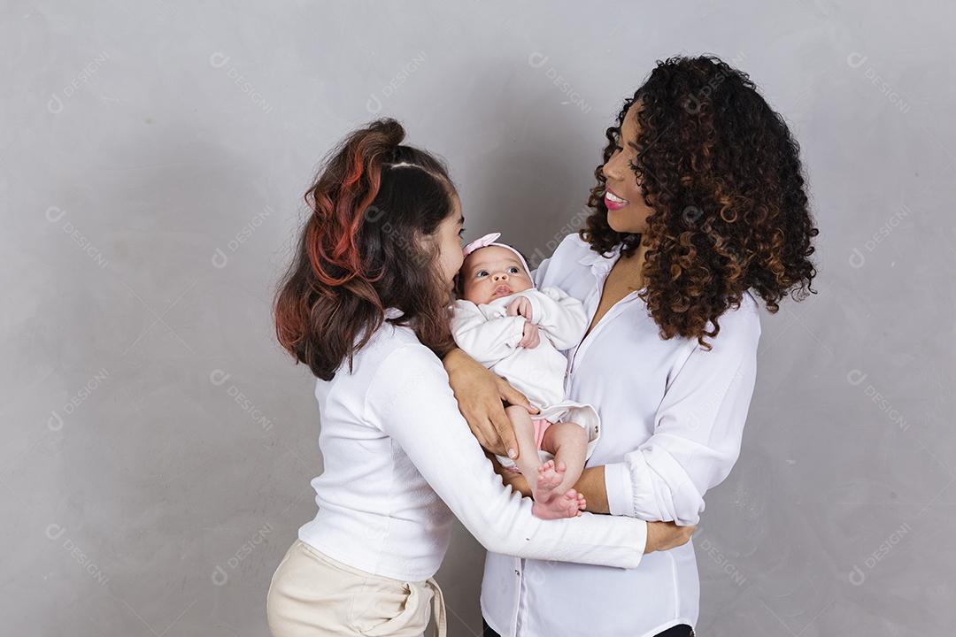 Linda jovem mãe afro com suas filhas em fundo cinza. Mãe, filha e bebê