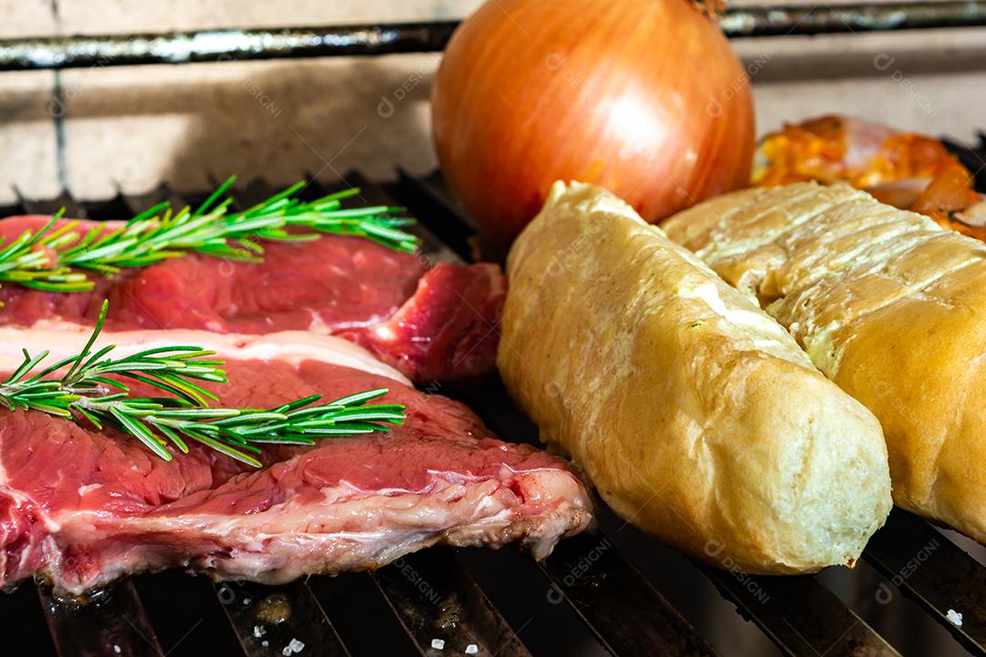 grelha com itens tradicionais do churrasco brasileiro, bife do lombo, pão de alho. coxinha de frango, cebola.